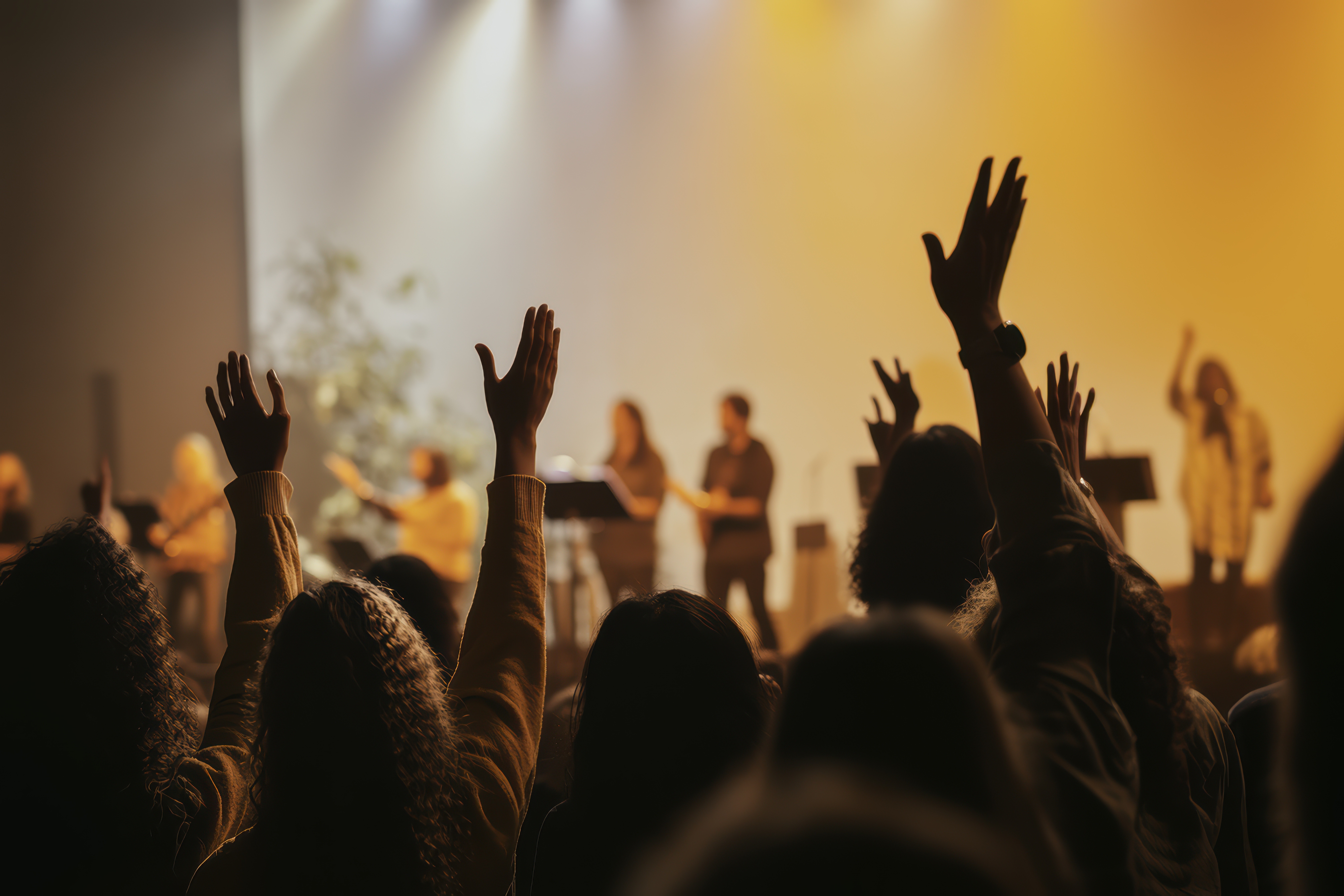 People praising God and Jesus at a church service with a worship band in the background